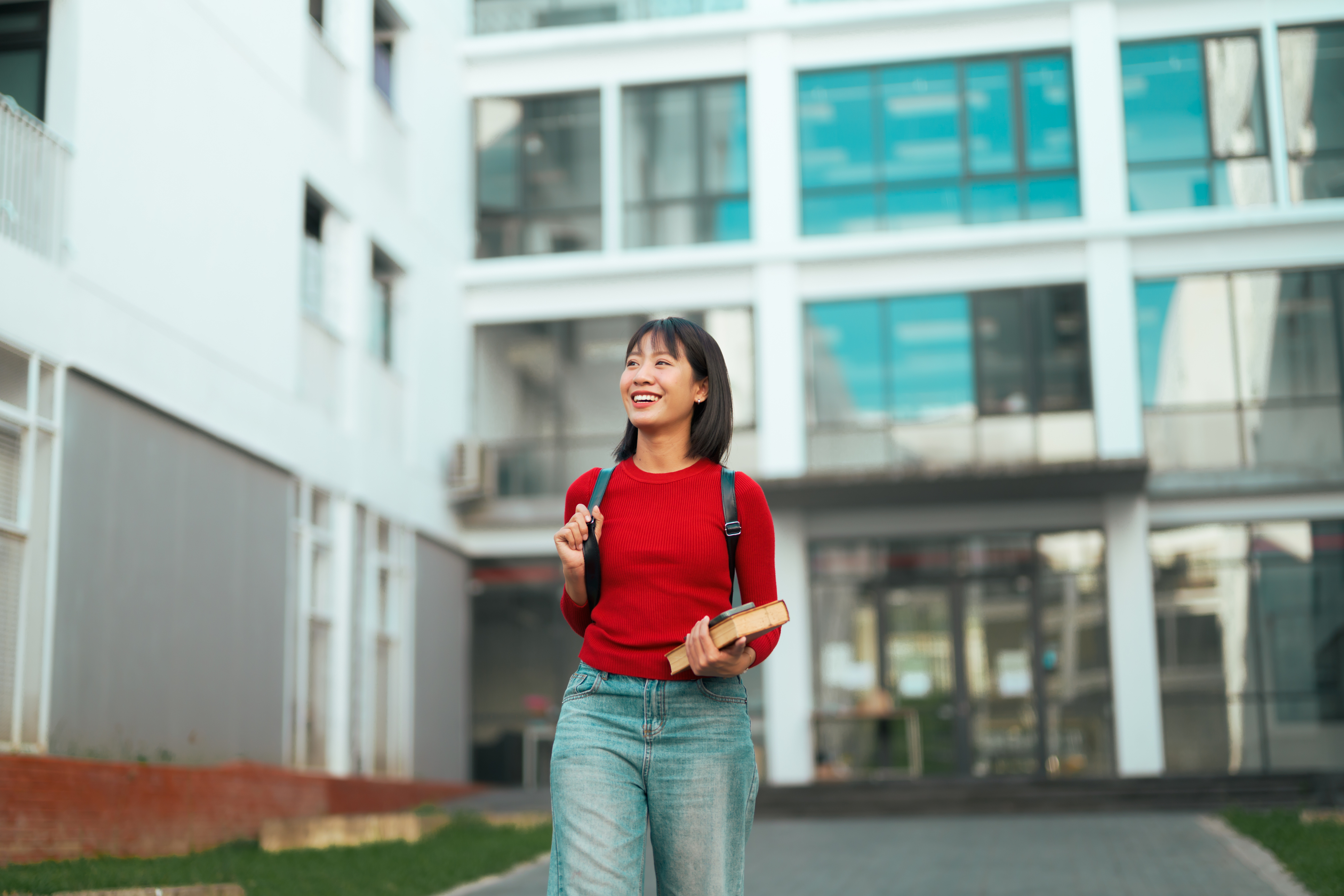Happy female student walking outdoors on university